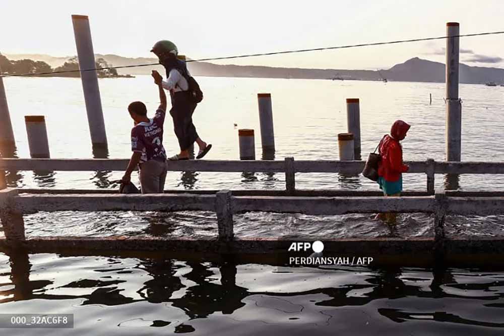 Gambaran seorang pelajar putri yang harus dituntun saat melewati titian kayu saat berangkat ke sekolah. (Foto: Perdiansyah/@ferdiawed)
